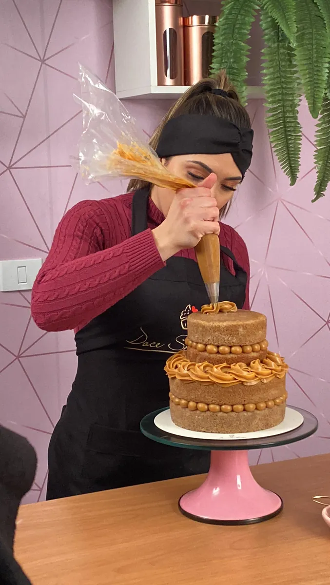 Naama confeitando um bolo com bico